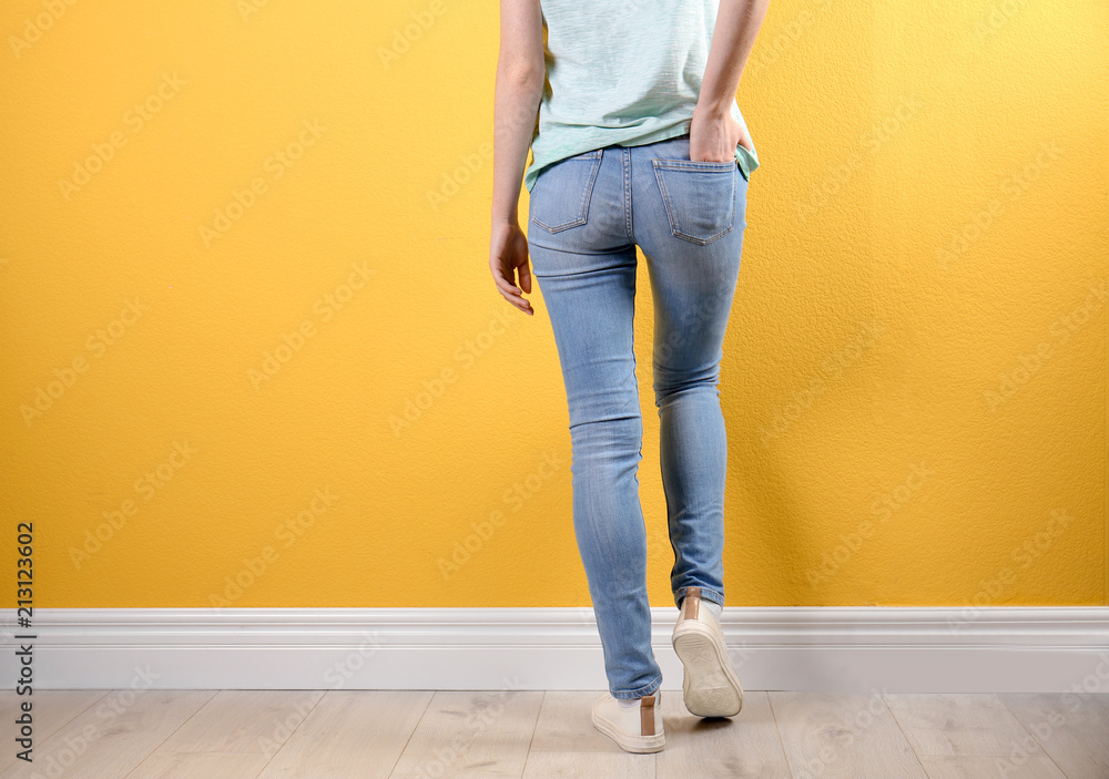 Young woman in stylish jeans near color wall Young woman in stylish jeans near color wall