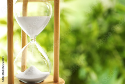 Hourglass with flowing sand on blurred background. Time management