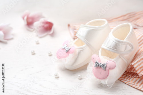 Pair of cute baby sandals and clothes on table