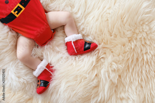 Cute baby in Christmas costume lying on fur rug