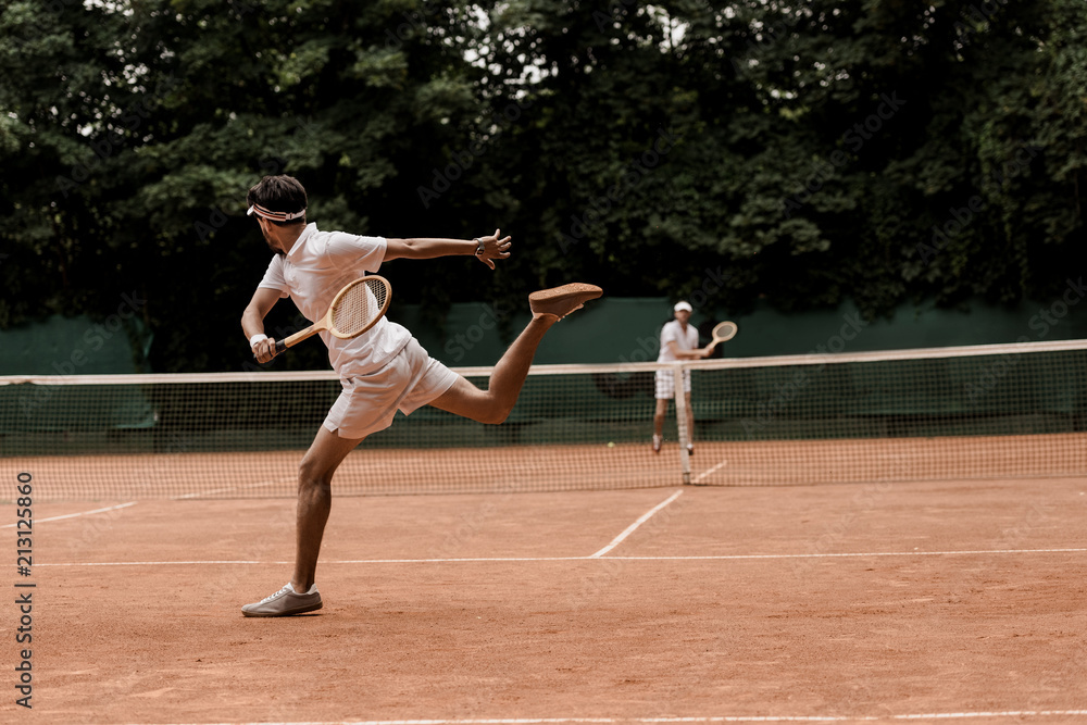 retro styled men playing tennis at court