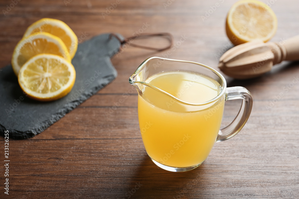Glass jug with fresh lemon juice on wooden table Glass jug with fresh lemon juice on wooden table