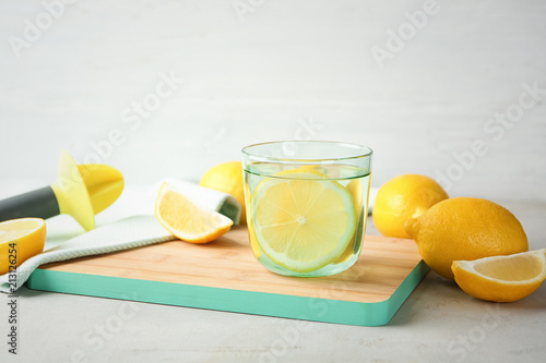 Glass of water with lemon slice on wooden board