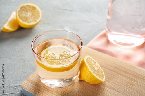 Glass of water with lemon slice on wooden board