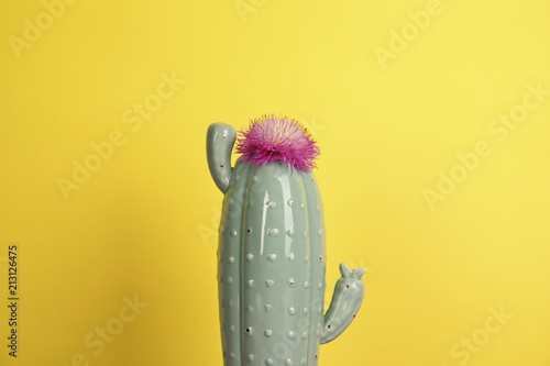 Trendy cactus shaped ceramic vase with flower on color background