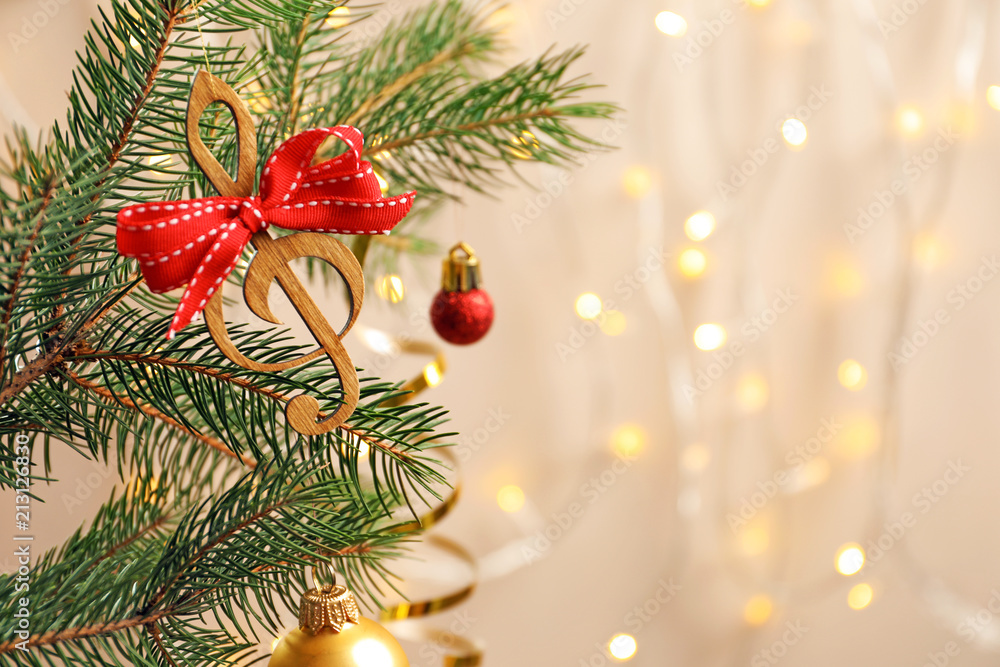Fir tree branch with wooden treble clef on blurred background. Christmas music concept Fir tree branch with wooden treble clef on blurred background. Christmas music concept