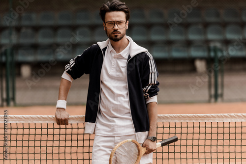 handsome tennis player looking at camera at tennis court and holding racket © LIGHTFIELD STUDIOS