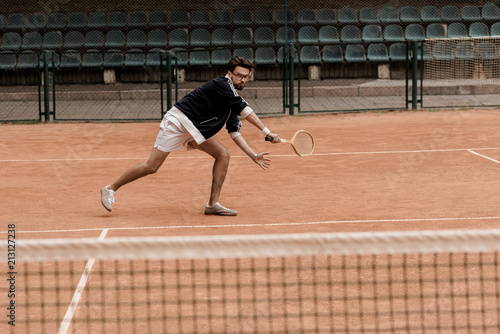 retro styled handsome man playing tennis with racket at tennis court © LIGHTFIELD STUDIOS