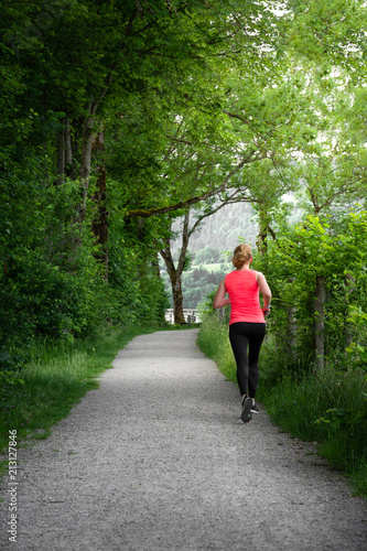 Young woman running along path next to lake