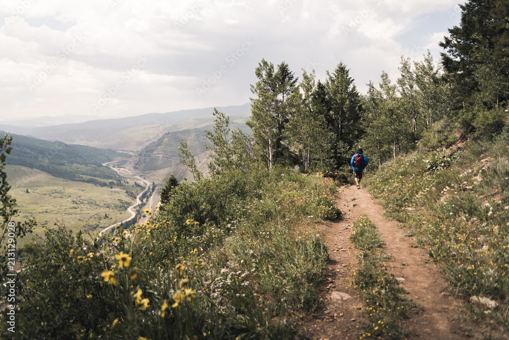 A man hiking on at the top of a trail in Colorado during summer. 