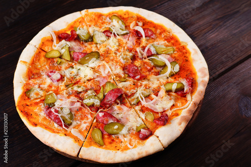 Delicious sliced napoli pizza with salami and gherkins on wood, close up. Italian food, restaurant menu photo