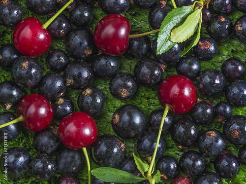 Black currant and red cherries on the grass as background