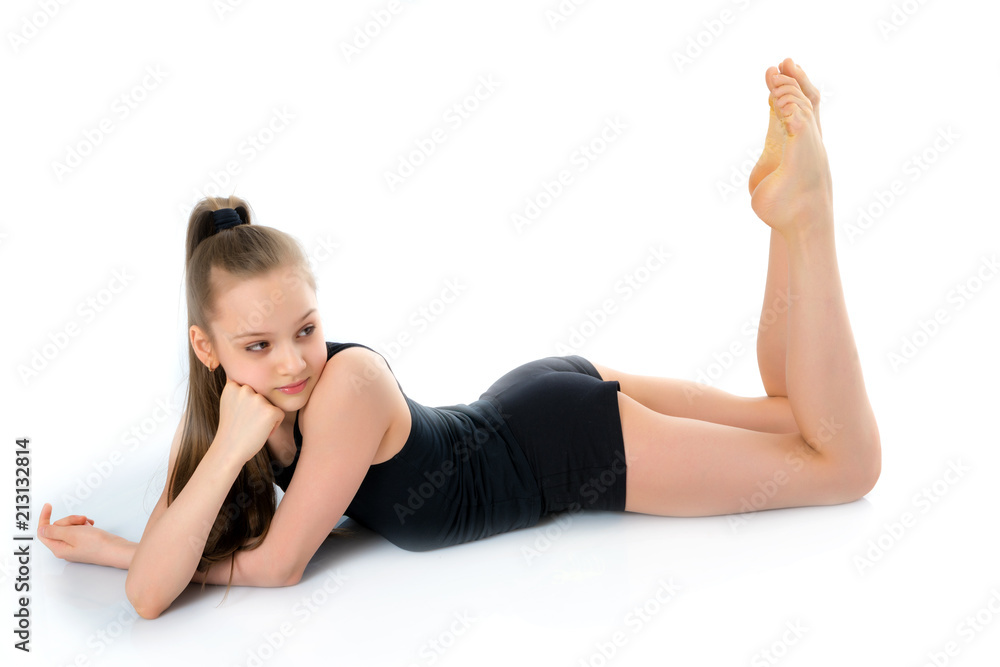 The little gymnast perform an acrobatic element on the floor.