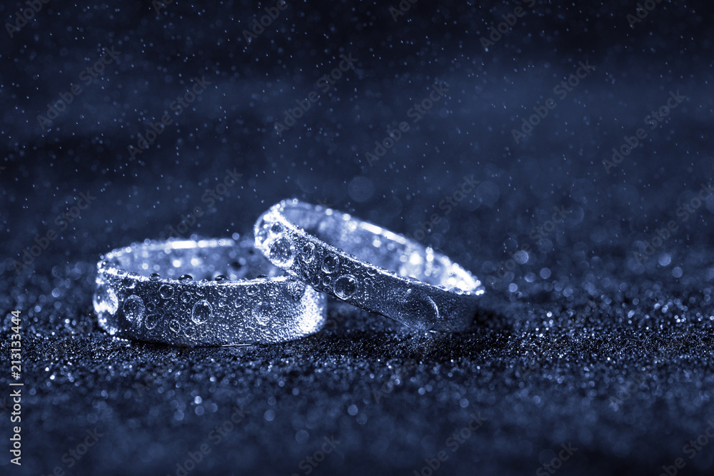 custom made wallpaper toronto digitalTwo wedding rings with water drops on blue background with copy space.