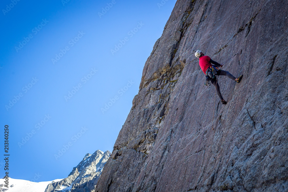 A climber is being belayed down the cliff face