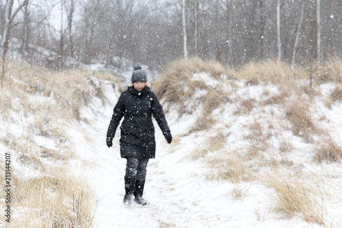 A woman walks through the snowy sand dunes of western Michigan in the winter