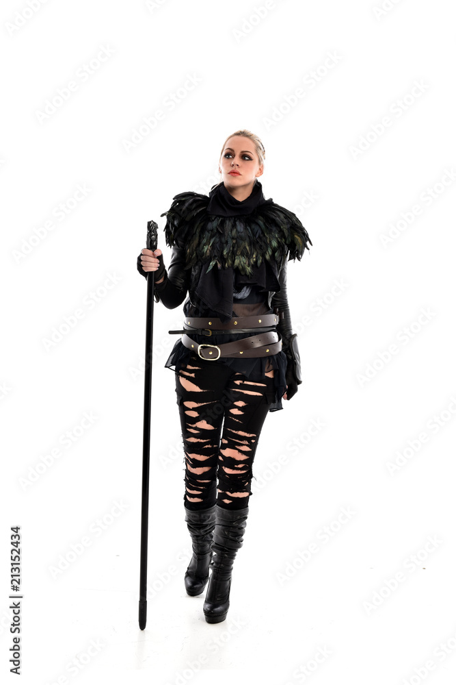 full length portrait of blonde girl wearing black gothic outfit, holding a staff. standing pose, isolated on white studio background. full length portrait of blonde girl wearing black gothic outfit, holding a staff. standing pose, isolated on white studio background.