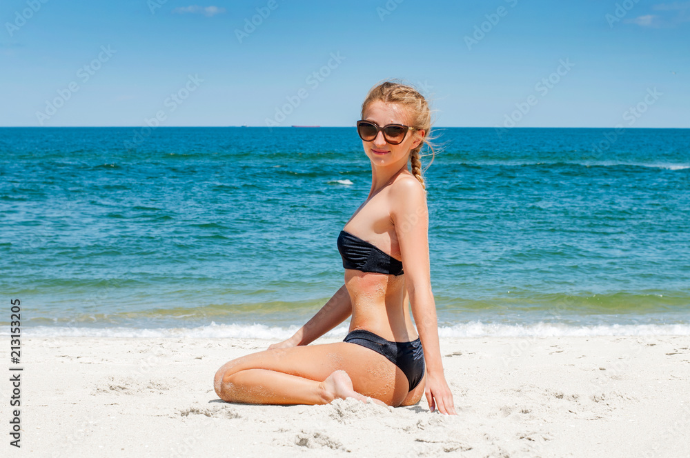 Beautiful woman in bikini sitting on the beach Beautiful woman in bikini sitting on the beach