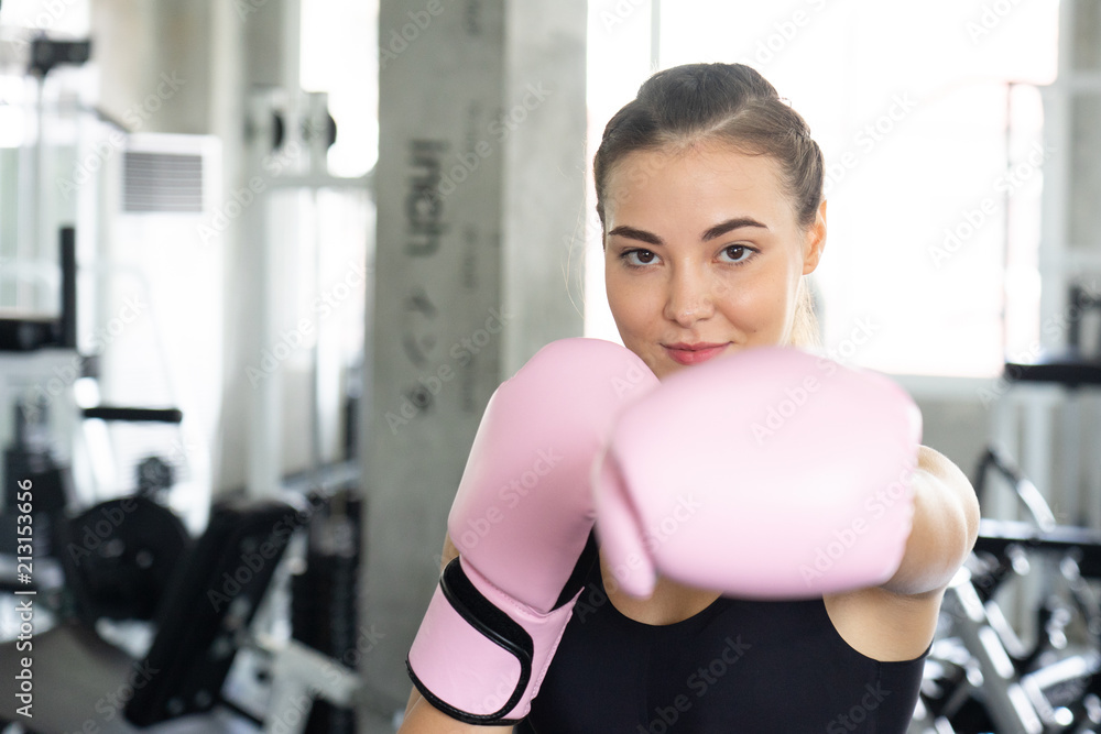 Fototapeta premium Boxing young beautiful woman exercises with pink glovw.She doing exercise and punching .