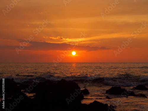 Sunset over ocean with lava rocks of Holoholokai Beach in the foreground © Eric BVD