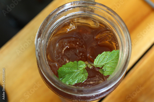 A cup of ice lemon tea with its leaf, served at a cafe