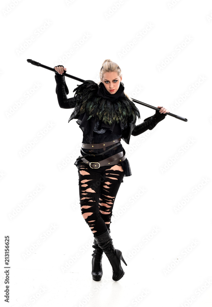 full length portrait of blonde girl wearing black gothic outfit, holding a staff. standing pose, isolated on white studio background. full length portrait of blonde girl wearing black gothic outfit, holding a staff. standing pose, isolated on white studio background.