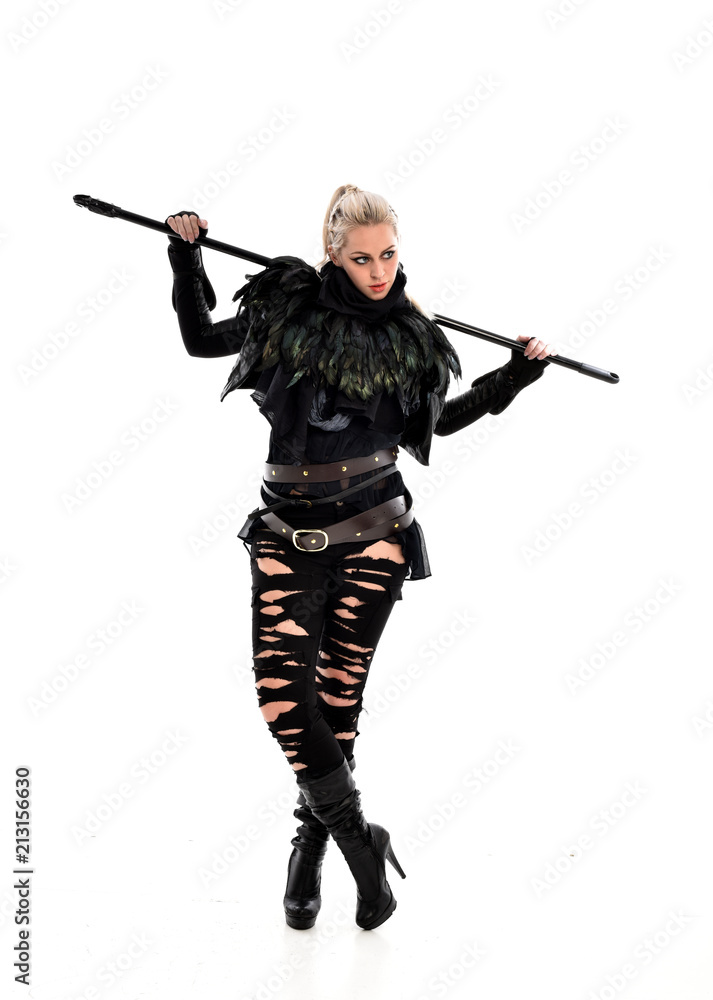 full length portrait of blonde girl wearing black gothic outfit, holding a staff. standing pose, isolated on white studio background. full length portrait of blonde girl wearing black gothic outfit, holding a staff. standing pose, isolated on white studio background.