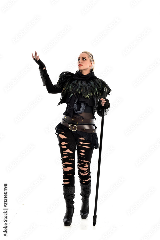 full length portrait of blonde girl wearing black gothic outfit, holding a staff. standing pose, isolated on white studio background. full length portrait of blonde girl wearing black gothic outfit, holding a staff. standing pose, isolated on white studio background.