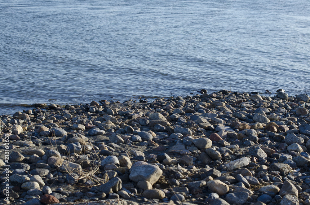 Obraz premium The small rock shoreline of the dry and dead great salt lake in the summer sun. 