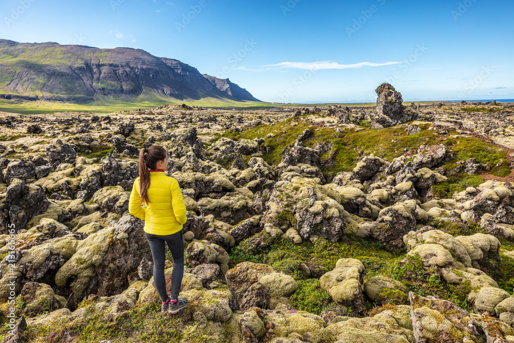Iceland travel - woman walking hiking on lava fields in Iceland covered in moss - amazing nature landscape. Summer travel.