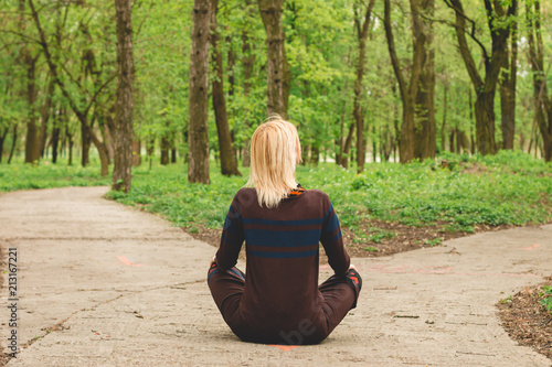 the girl is sitting on the road in the direction of two roads.