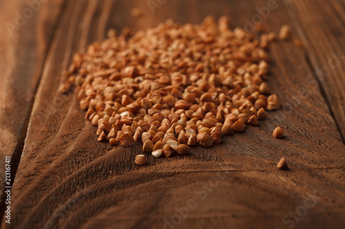 Wooden Board . On the Board scattered brown grain buckwheat.