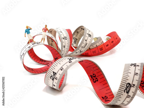 Miniature woman standing near measuring tape, thinking of weight loss and slim body. Healthy lifestyle concept.