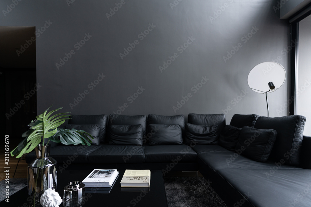 Cozy black leather sofa in composition with minimal black and white floor  lamp with gray painted