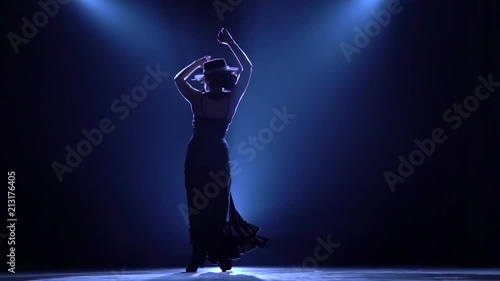 Girl is dancing castanets in her hands dancing. Llight from behind. Smoke background. Silhouette. Slow motion