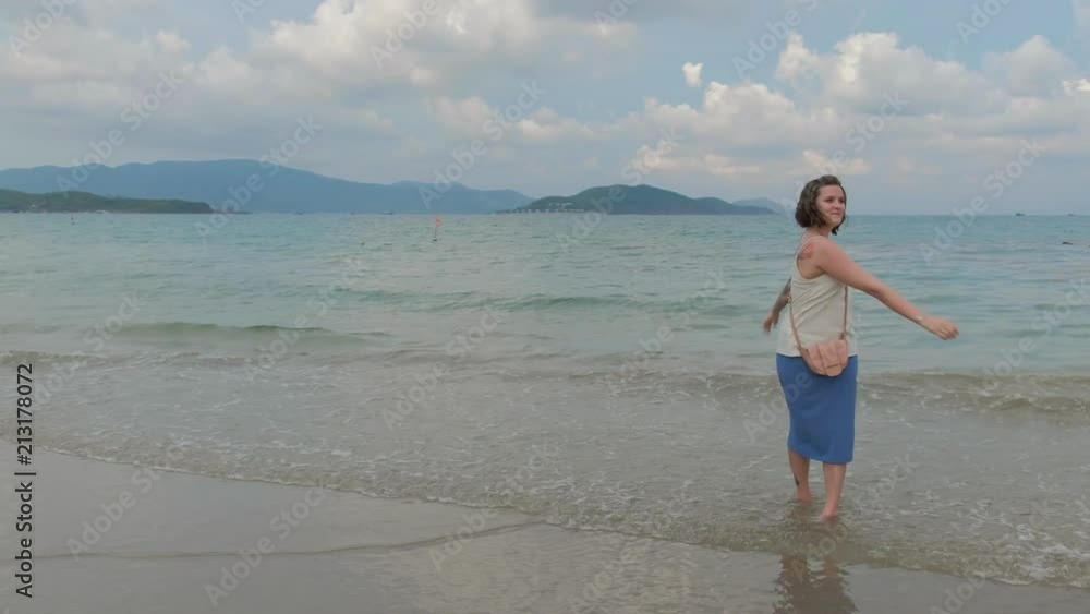 A beautiful tattooed woman is walking by the ocean shore, strerching and enjoying the view A beautiful tattooed woman is walking by the ocean shore, strerching and enjoying the view