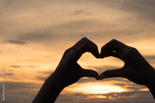 Hands as heart shape with beautiful sky in warm color twilight sunset background love and romantic concept.