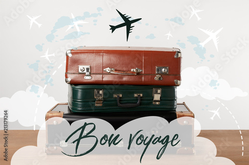 Fototapeta Stacked old leather travel bags with airplanes and Bon voyage (have a nice trip)