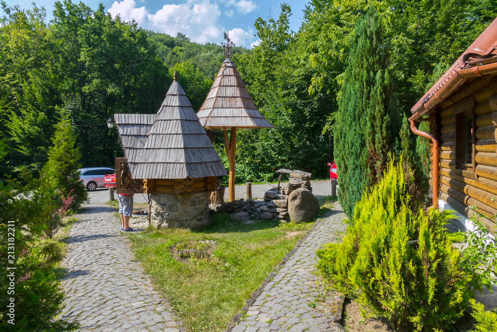 a wooden house with a well in the courtyard facing a stone in the middle of the forest. the car came to visitors