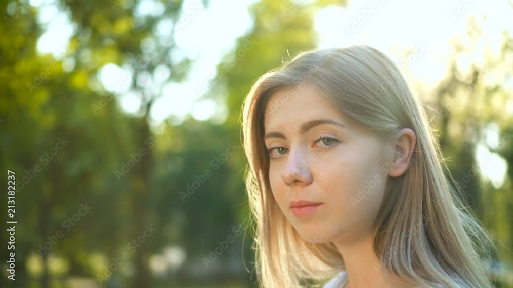 Girl portrait. Beautiful blonde young woman looking at camera on sunny summer or spring day outside at sunset Girl portrait. Beautiful blonde young woman looking at camera on sunny summer or spring day outside at sunset