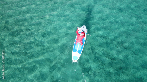 Photography Aerial drone of Santa Claus paddle surfing in Caribbean turquoise clear waters