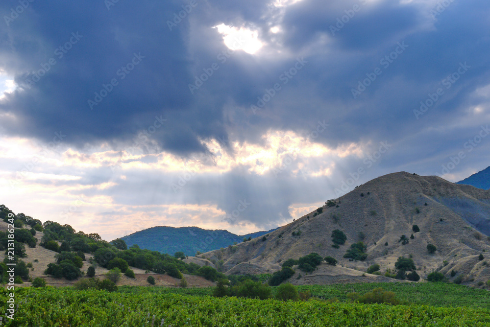 Naklejka premium The tops of a rocky green mountain range against a cloudy sky background