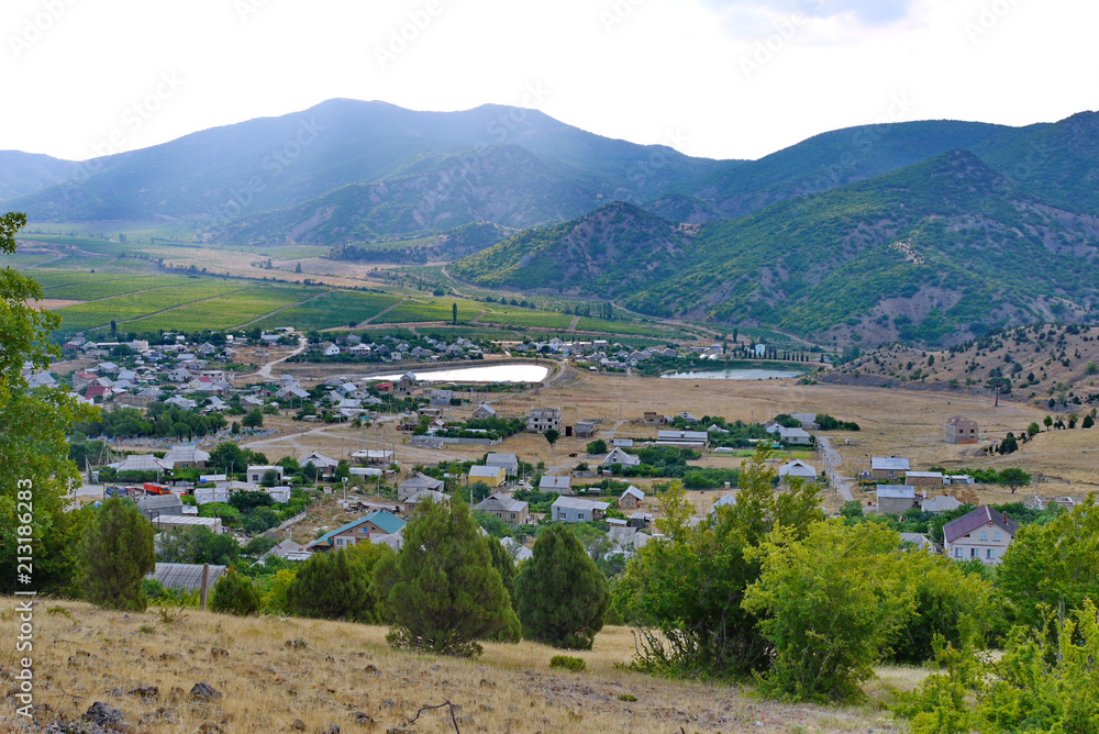 Fototapeta premium industrial unpopular small town in the valley of mountains with small ponds and green fields