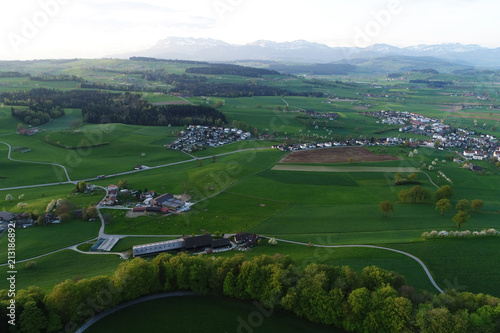 Swiss lowland with villages, farms and the Alps in the background on a spring morning