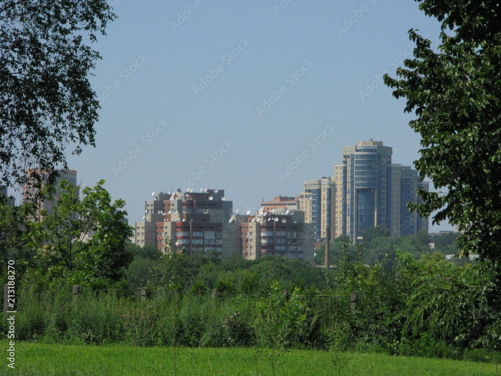 Urban high-rise buildings against a background of green trees and shrubs