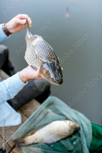 Fisherman holding caught fish during the fishing on the lake