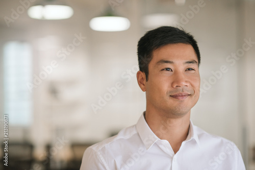 Smiling Asian businessman thinking of new ideas in his office
