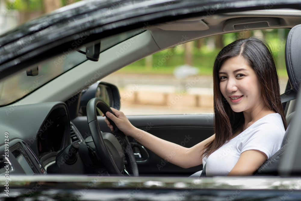 Young beautiful asian woman with a nice smile driving in a car.