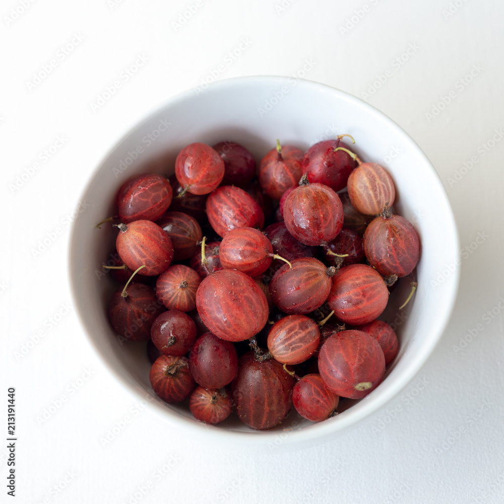 Obraz premium Schale mit roten Stachelbeeren auf weißem Untergrund