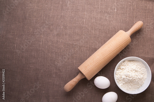 Baking ingredients. Flour, eggs, wheat and rolling pin on  table cloth. Rustic. Copy space